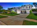 Charming two-story home featuring a three-car garage, well-manicured lawn, and a beautifully landscaped front yard at 12965 Satin Lily Dr, Riverview, FL 33579
