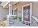 Covered porch with stone pillar, decor, and a dark wood front door adorned with a decorative wreath at 12965 Satin Lily Dr, Riverview, FL 33579