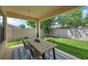 Covered outdoor patio area with a dining table set and a view of the fenced backyard and greenery at 29219 Perilli Pl, Wesley Chapel, FL 33543