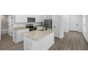 Modern kitchen with stainless steel appliances, granite countertops, an island, and wood flooring at 29535 Fedora Cir, Brooksville, FL 34602