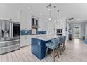 Modern kitchen featuring white cabinets, a blue island with seating, and stainless steel appliances at 4583 Emprise Way, Land O Lakes, FL 34638