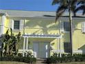 Charming yellow condo exterior with white trim, lush landscaping, and shared pergola entrance at 5242 Beach Se Dr, St Petersburg, FL 33705