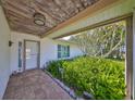 Inviting front porch area with brick flooring and tropical landscaping with lush ferns and greenery at 5785 Bay Pines Lakes Blvd, St Petersburg, FL 33708