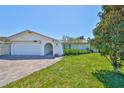 Charming single-story home featuring a well-maintained lawn, arched entryway and a brick-paved driveway at 5785 Bay Pines Lakes Blvd, St Petersburg, FL 33708