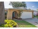 Single-story home with an arched entryway, an attached garage, and beautifully maintained landscaping at 8350 Monarch Cir, Seminole, FL 33772