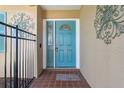 Close-up view of a teal front door, enhanced by decorative metalwork and a tiled porch at 8350 Monarch Cir, Seminole, FL 33772