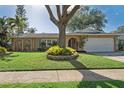 Inviting single-story home with mature landscaping, a well-manicured lawn, and an attached two-car garage at 8350 Monarch Cir, Seminole, FL 33772