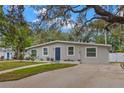 Well-maintained single-story home with a blue front door, a spacious driveway, and simple landscaping at 121 Pennsylvania Ave, Palm Harbor, FL 34683