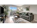 Bright living room with sliding glass doors to balcony, gray sofa and chair, wood-look flooring at 1400 Gandy N Blvd # 1701, St Petersburg, FL 33702