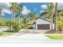 Inviting home boasting lush landscaping with palm trees, a paved driveway, and a two-car garage for ample parking at 2966 Longbrooke Way, Clearwater, FL 33760