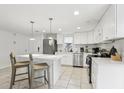 Bright kitchen with white cabinetry, stainless steel appliances, tile floors, and a breakfast bar at 4902 Blue Heron Dr, New Port Richey, FL 34652