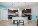 Modern kitchen featuring stainless steel appliances, black cabinetry, an island with bar seating, and dining table at 7869 Timberview Loop, Wesley Chapel, FL 33545