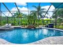 Inviting screened-in pool area features a waterfall feature, lush landscaping, and comfortable lounge seating at 8420 Dunham Station Dr, Tampa, FL 33647