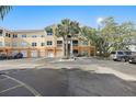 Exterior of condo building with parking lot showing garage access and palm trees on a clear day at 10764 70Th Ave # 1205, Seminole, FL 33772