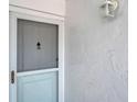 Close up of unit 140's exterior white front door and hardware with stucco exterior at 1655 S Highland Ave # D140, Clearwater, FL 33756