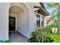 Inviting front entryway featuring a dark wood front door, brick flooring, and lush landscaping around the entrance at 16840 Whisper Elm St, Wimauma, FL 33598
