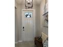 Well-lit foyer with a white front door, a small bench, a decorative light fixture, and a coastal themed art at 16840 Whisper Elm St, Wimauma, FL 33598