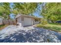View of the home featuring brick accents, a one-car garage, and a spacious driveway with mature shade trees at 1710 S Lake Ave, Clearwater, FL 33756