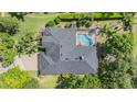 Aerial view of a home with a dark roof, screened-in pool, lush landscaping, and brick driveway at 19708 Wellington Manor Blvd, Lutz, FL 33549