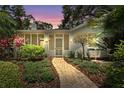 Serene home entrance at twilight, showcasing a brick walkway leading to a screened porch, framed by lush landscaping at 250 Aberdeen St, Dunedin, FL 34698