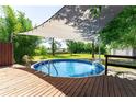 Inviting above ground pool with wooden deck and shaded canopy, perfect for outdoor relaxation at 3319 Fox Ridge Blvd, Wesley Chapel, FL 33543