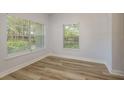 Inviting living room with wood-look flooring, white walls, two windows with views, and neutral decor at 3583 Wembley Way # 101, Palm Harbor, FL 34685