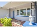 Charming front porch with decorative lamps, a tiled floor, and a blue front door at 4256 Rudder Way, New Port Richey, FL 34652