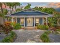 Charming home featuring a landscaped yard, brick walkway, and covered front porch at dusk at 7708 N Arden Ave, Tampa, FL 33604