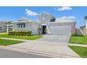 Charming single-story home featuring a well-manicured lawn, a brick driveway, and a stylish blue front door at 8919 Drummer Plank Dr, Wesley Chapel, FL 33545