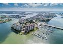 Beautiful aerial view showcasing waterfront condos, a marina, and the coastal landscape with clear blue skies at 9525 Blind Pass Rd # 508, St Pete Beach, FL 33706