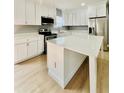 Modern kitchen featuring white cabinets, stainless steel appliances, and a center island with quartz countertop at 1002 E North Bay St, Tampa, FL 33603