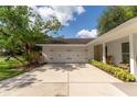 Attached two-car garage featuring white doors and a concrete driveway, adjacent to a well-maintained lawn at 10609 Orange Grove Dr, Tampa, FL 33618