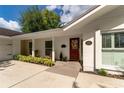 Welcoming front porch with rocking chairs, a red door, and manicured landscaping at 10609 Orange Grove Dr, Tampa, FL 33618