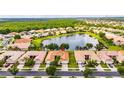 Aerial view of the home showcasing a lake view, tile roof, well-manicured lawn, and neighborhood at 16261 Amethyst Key Dr, Wimauma, FL 33598