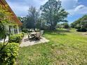 An inviting backyard with a patio set and lush green grass surrounded by mature trees at 1681 Macdonnell Ct, Palm Harbor, FL 34684