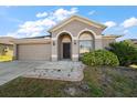 Well-maintained home with a two-car garage, arched entryway, and a tidy, green lawn at 18314 Waydale Loop, Hudson, FL 34667