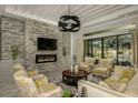 Bright living room featuring a stone fireplace, modern lighting and backyard views at 18483 Purple Creek Ln # Lot 1, Lutz, FL 33549