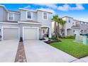 Charming two-story townhome with a one-car garage, blue front door, and well-maintained landscaping at 2265 Alee Ln, Wesley Chapel, FL 33543