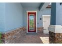 Inviting entryway featuring a red front door with brick accents and a covered porch at 2835 Hilliard Dr, Wesley Chapel, FL 33543