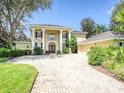 Stunning home with classic architecture, prominent columns, and a paver driveway, enveloped by mature landscaping at 4848 Quill Ct, Palm Harbor, FL 34685