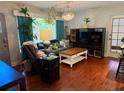 Comfortable living room featuring a large window with curtains, chandelier, sofa, and wood-look flooring at 5045 2Nd S Ave, St Petersburg, FL 33707