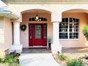 Inviting front entrance with a red front door, sidelights, and decorative columns at 8120 Greenbrier Ct, Spring Hill, FL 34606