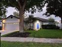 Charming home exterior featuring a blue front door, manicured lawn, and mature trees at 824 Greenbelt Cir, Brandon, FL 33510