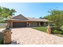 Charming home exterior featuring a brick driveway, stone accents, and professionally manicured landscaping at 113 Garland Cir, Palm Harbor, FL 34683