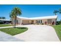 Inviting home showcasing a lush lawn, mature landscaping, and a convenient two-car garage, and circular driveway at 13797 Pinecrest Dr, Largo, FL 33774