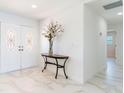 Bright foyer features double doors, marble floors, a console table, and fresh white paint at 13797 Pinecrest Dr, Largo, FL 33774