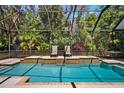 Screened-in pool with waterfall feature, patio chairs and table, and lush greenery creating a private backyard oasis at 15930 Sorawater Dr, Lithia, FL 33547