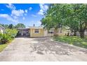 Single-story home with a long driveway, screened-in porch, and mature trees at 3214 W Rogers Ave, Tampa, FL 33611