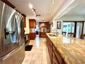 Open kitchen with stainless steel appliances, wooden cabinets, granite countertops and tile flooring at 3240 Sand Key Dr, Palm Harbor, FL 34684