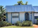 Charming home featuring a blue metal roof, stucco siding, an arched doorway, and neatly manicured landscaping at 4237 Tamargo Dr # 4237, New Port Richey, FL 34652
